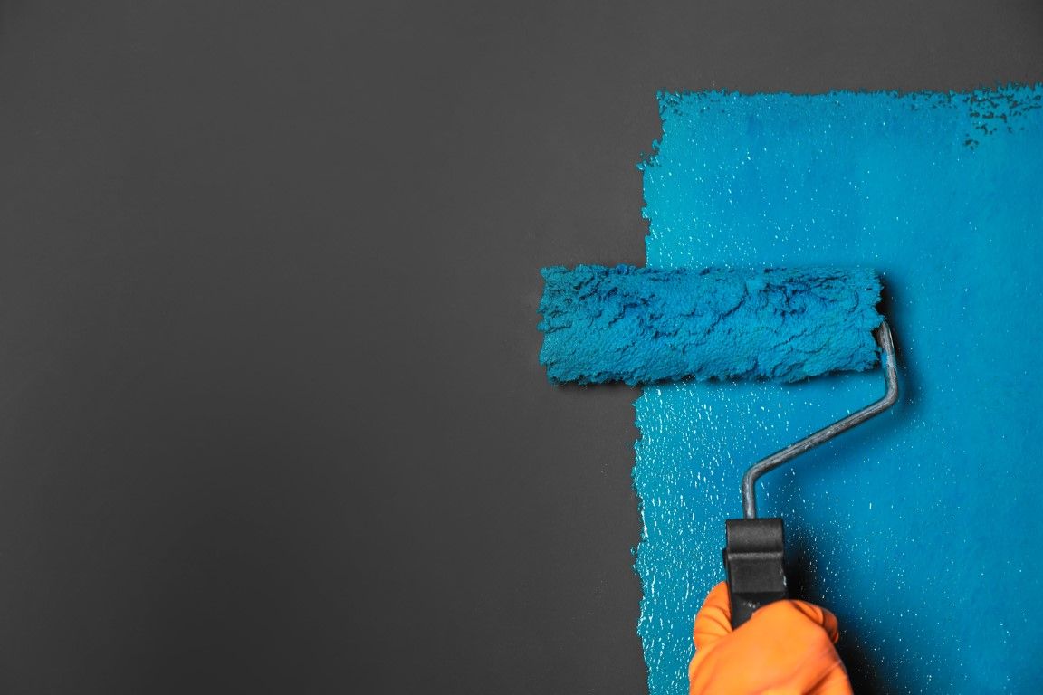Painter working from a ladder on exterior siding and trim